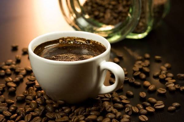 brewed coffee in mug and on table are coffee beans